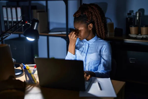 African woman working at the office at night tired rubbing nose and eyes feeling fatigue and headache. stress and frustration concept.