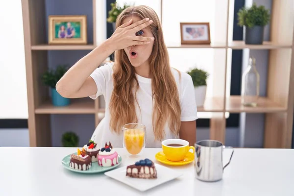 Young Caucasian Woman Eating Pastries Breakfast Peeking Shock Covering Face — 스톡 사진