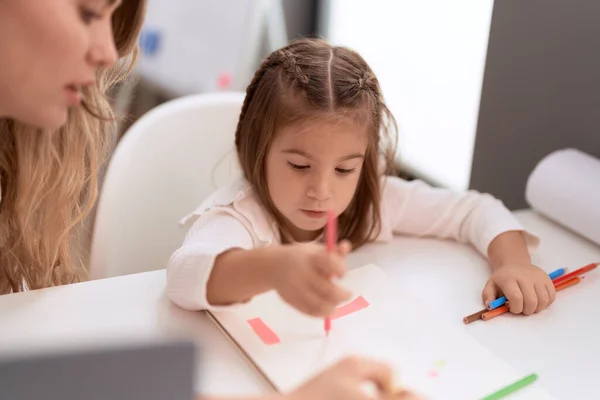 Lehrerin Und Kleinkind Sitzen Auf Tisch Und Zeichnen Auf Notizbuch — Stockfoto