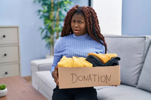 アフリカの女性は衝撃的な顔で慈善のための寄付箱を保持し 懐疑的で皮肉 オープン口で驚いています — ストック写真