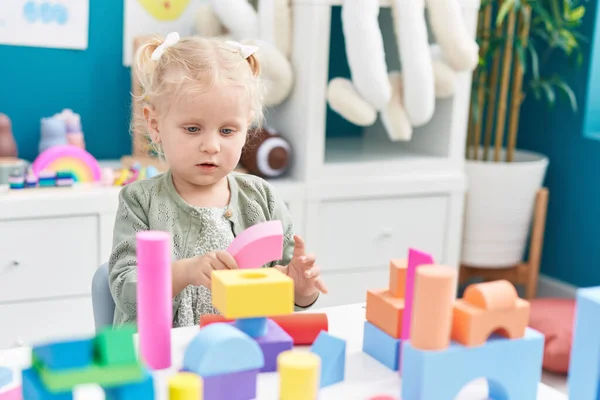 stock image Adorable blonde girl playing with construction blocks sitting on table at kindergarten