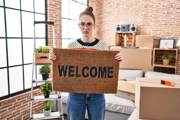 Young Hispanic Girl Holding Welcome Doormat Skeptic Nervous Frowning Upset — Stock Photo, Image