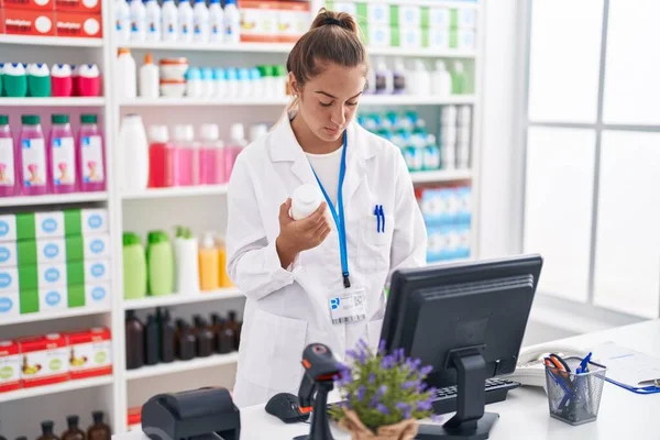 Young Beautiful Hispanic Woman Pharmacist Using Computer Holding Pills Bottle — 图库照片