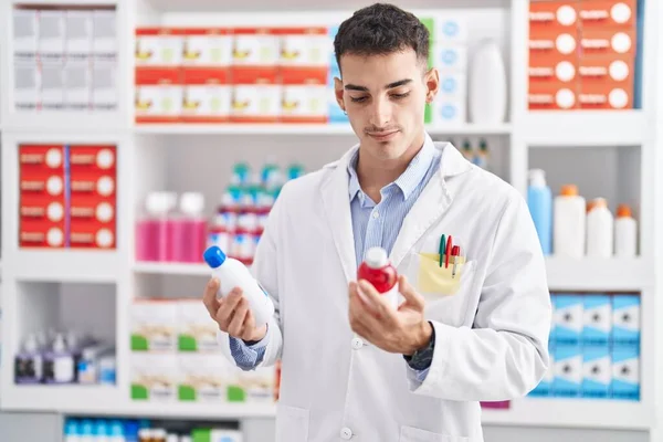 Joven Farmacéutico Hispano Sonriendo Confiado Sosteniendo Botellas Medicamentos Farmacia —  Fotos de Stock