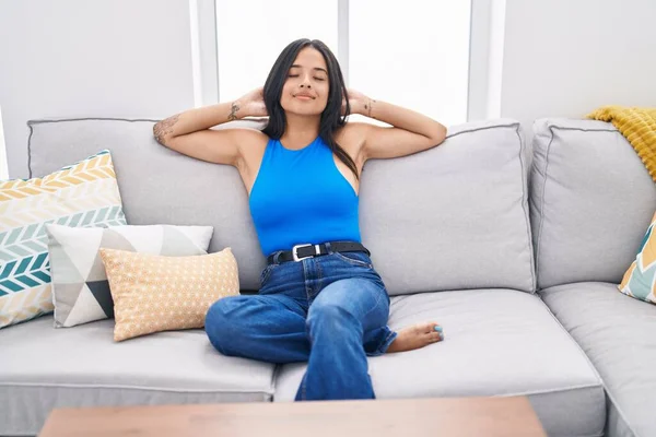 Young Hispanic Woman Relaxed Hands Head Sitting Sofa Home — Zdjęcie stockowe