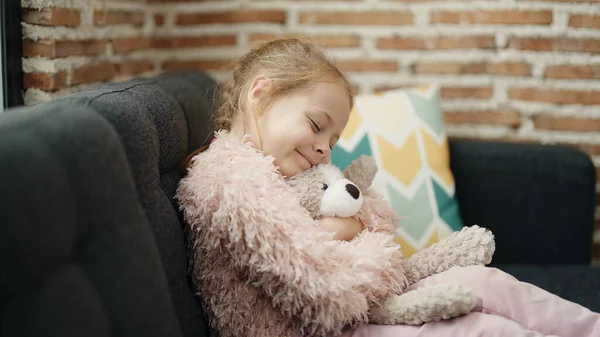 Adorable Blonde Girl Hugging Teddy Bear Sitting Sofa Home — 图库照片