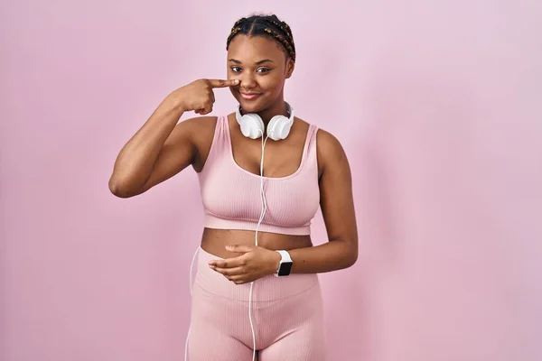 Afroamerikansk Kvinna Med Flätor Sportkläder Och Hörlurar Som Pekar Med — Stockfoto