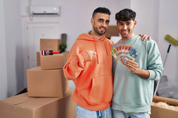 Young Hispanic Gay Couple Moving New Home Holding Banknotes Pointing — Zdjęcie stockowe