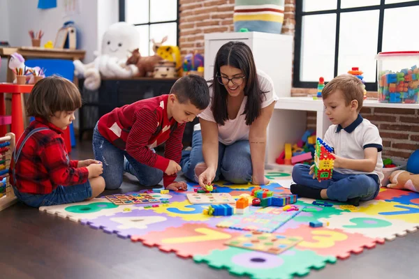 幼儿园的老师和一群男孩子坐在地板上玩数学拼图游戏 — 图库照片