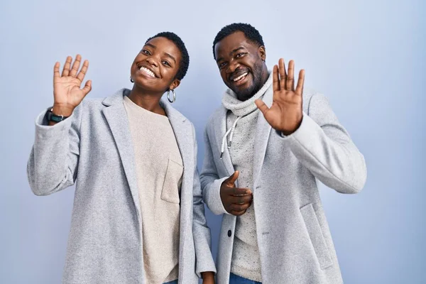 一对年轻的非洲裔美国夫妇站在蓝色的背景上 等待着打招呼 高兴地微笑着 友好地欢迎 — 图库照片