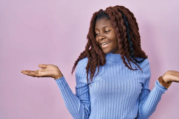 Afrikanerin Steht Lächelnd Auf Rosa Hintergrund Und Zeigt Mit Beiden — Stockfoto