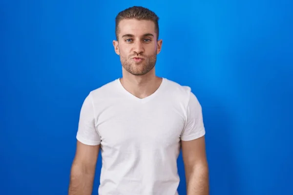 Young Caucasian Man Standing Blue Background Looking Camera Blowing Kiss — Foto de Stock