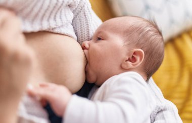 Anne oğul kanepede oturup bebeği emziriyorlar.