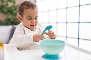 Tapılası İspanyol bebek gülerek evde şezlongda oturuyor.