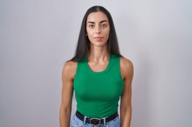Young woman standing over isolated background relaxed with serious expression on face. simple and natural looking at the camera. 