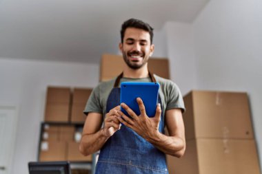 Young hispanic man business worker using touchpad at storehouse