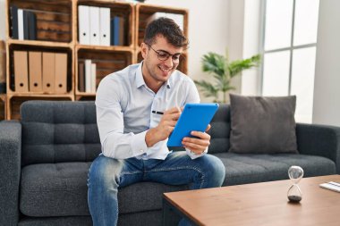 Psikoloji kliniğinde dokunmatik pedini kullanarak gülümseyen genç İspanyol psikolog.