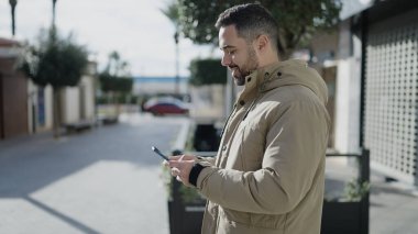 Sokakta akıllı telefon kullanan, kendine güvenen genç bir İspanyol.