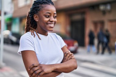 Sokakta kollarını kavuşturmuş Afro-Amerikalı bir kadın.