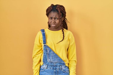 African woman standing over yellow background skeptic and nervous, frowning upset because of problem. negative person. 