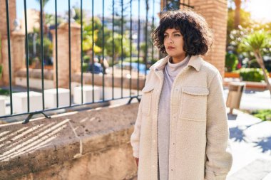 Young beautiful hispanic woman looking to the side with serious expression at street