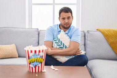 İspanyol adam evde televizyon seyrediyor. Kanepede şüpheci ve gergin oturuyor. Problemden dolayı surat asıyor. negatif kişi. 