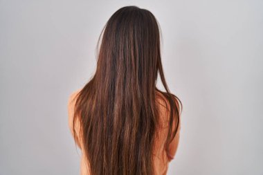Young brunette woman standing over white background standing backwards looking away with crossed arms 