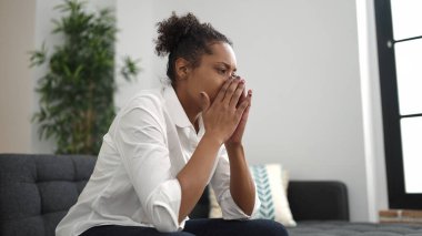 African american woman sitting on sofa with stressed expression at home