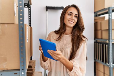 Young hispanic woman smiling confident using touchpad at storehouse