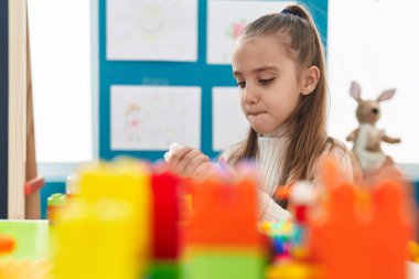 Anaokulundaki masada oturan, inşaat bloklarıyla oynayan sevimli İspanyol kız.