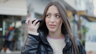 Genç ve güzel İspanyol kadın gülümsüyor. Caddedeki akıllı telefondan kendine güvenen bir sesli mesaj dinliyor.