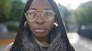 African woman standing with serious expression wearing glasses at park