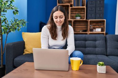 Genç ve güzel İspanyol kadın dizüstü bilgisayar kullanıyor. Evde kahve içiyor.