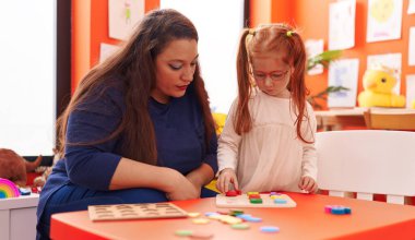 Teacher and student playing with maths puzzle game at kindergarten