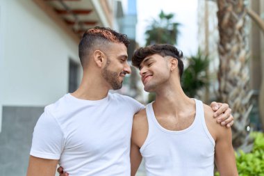 Two hispanic men couple smiling confident hugging each other at street