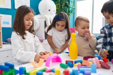 Group of kids playing with construction blocks sitting on table at kindergarten