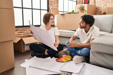 Erkek ve kadın, gülümseyen ve kendine güvenen bir çift yeni evinde boya rengi seçiyor.
