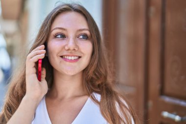 Genç sarışın kadın gülümsüyor. Kendine güveni tam. Akıllı telefondan konuşuyor.