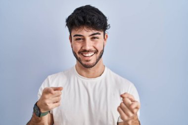 Hispanic man with beard standing over white background pointing fingers to camera with happy and funny face. good energy and vibes. 