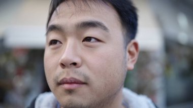 Young chinese man looking to the side with serious expression at street
