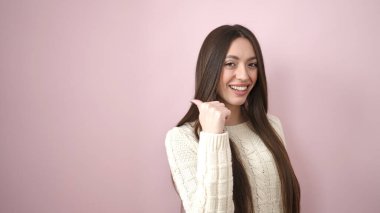 Young beautiful hispanic woman smiling confident pointing with finger to the side over isolated pink background