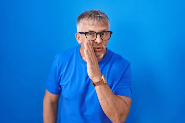 Hispanic Man Grey Hair Standing Blue Background Hand Mouth Telling — Stockfoto