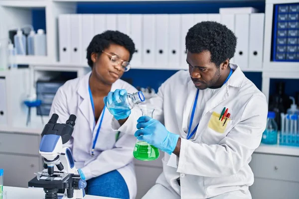 実験室で液体を測定するアフリカ系アメリカ人男性と女性科学者 — ストック写真