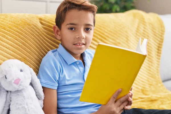 Adorable Hispanic Boy Reading Book Sitting Sofa Home — Stockfoto