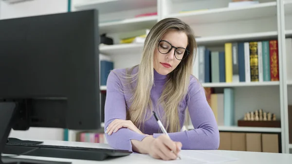 図書館大学でコンピュータ ライティングを使用して若いブロンドの女性の学生 — ストック写真