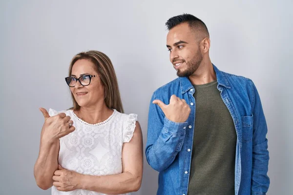 ヒスパニック系の母親と息子一緒に笑顔で立って幸せな顔を見て 親指で側面を指すアップ — ストック写真