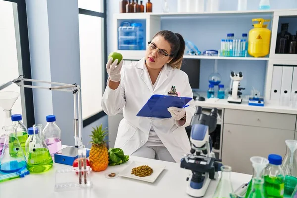 Young Beautiful Size Woman Scientist Holding Apple Reading Document Pharmacy — Foto Stock