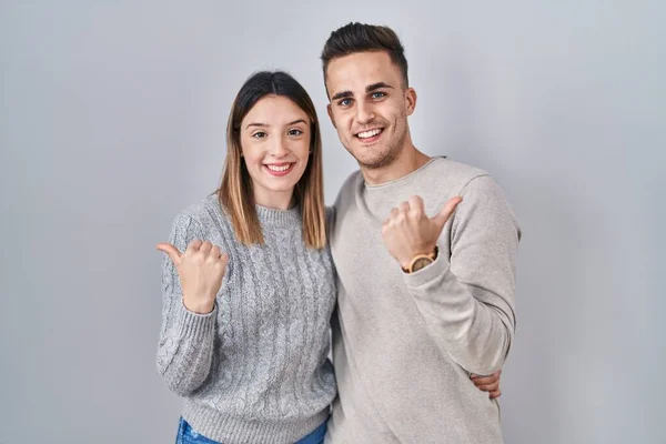 Unga Latinamerikanska Par Står Över Vit Bakgrund Pekar Baksidan Bakom — Stockfoto