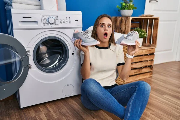 洗濯機にスニーカーを入れて若い女性は恐れていると驚きと驚きの表情でショックを受けました 恐怖と興奮した顔 — ストック写真