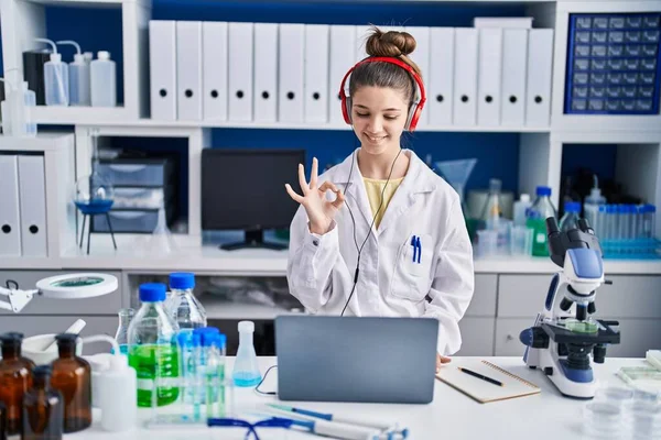 在科学家实验室工作的少女用手指做手势 微笑友善地表示出极好的象征 — 图库照片